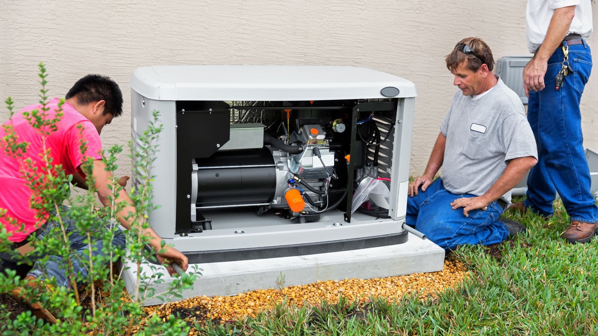 Technicians installing and servicing a residential generator near landscaped yard