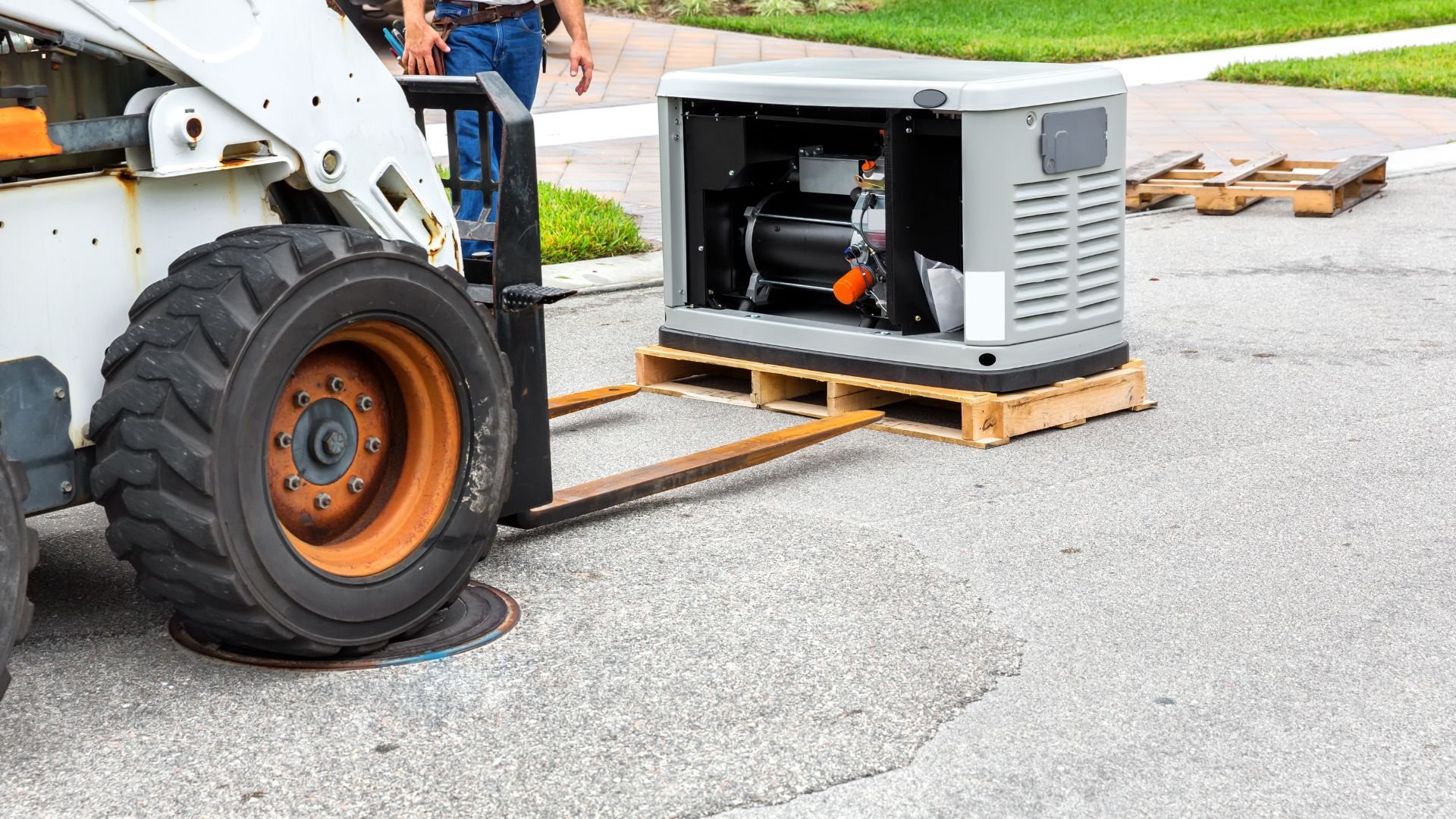Forklift moving generator on wooden pallet in outdoor industrial setting